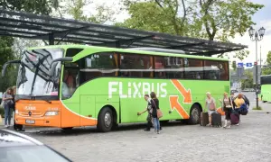 Zielony autobus Flixbus z pasażerami i bagażami na przystanku.