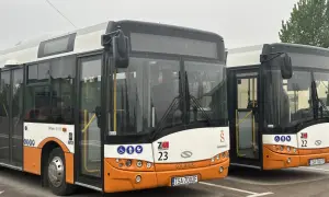 Dwa autobusy miejskie marki Solaris w kolorach białym i pomarańczowym, zaparkowane na placu.