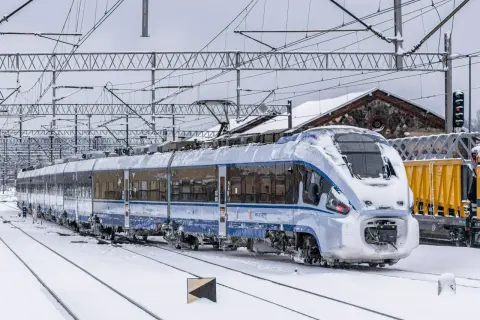 Pociąg PKP Intercity pokryty śniegiem na tle zimowego krajobrazu.