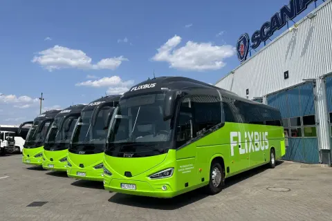 Rząd zielonych autobusów Flixbus zaparkowanych przed budynkiem z logo Scania.