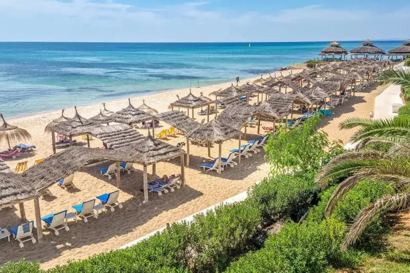 słoneczna plaża w kurorcie w Tunezji z turystami